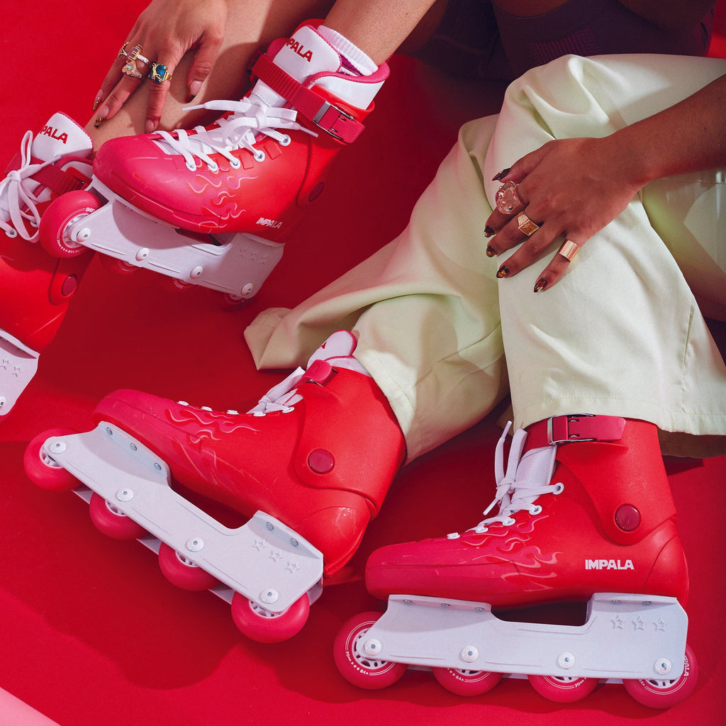 two women sitting on the floor with retro vintage red impala inline skates